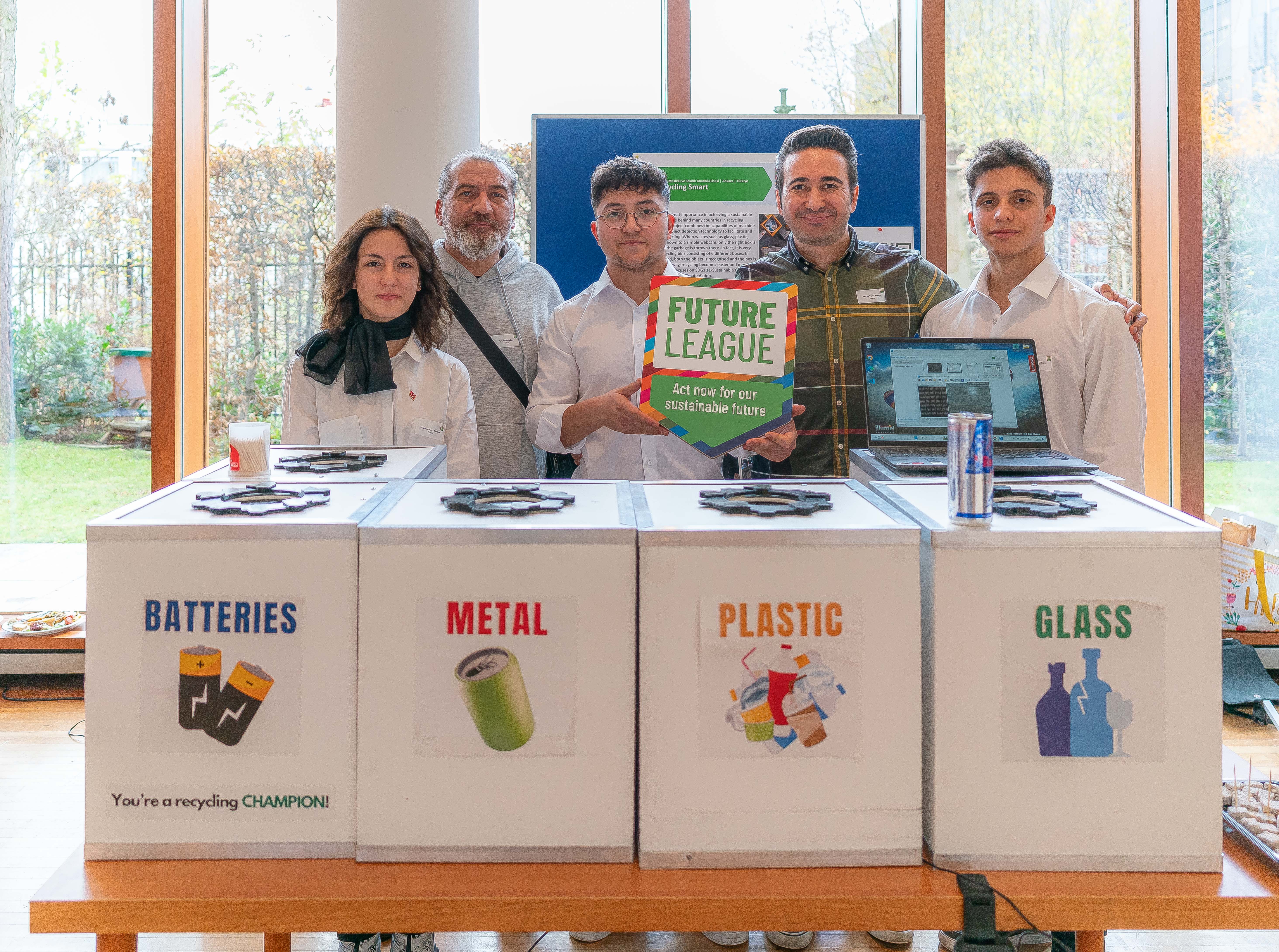 Two teachers and three students at a stand for the Future League competition