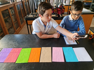 Students measuring the intensity of light of different coloured sheets